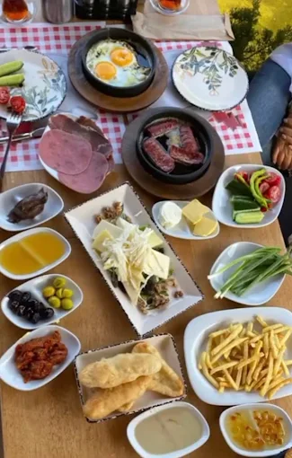 Gölet Cafe'nin ahşap masalı, aydınlık ve geniş iç mekânı